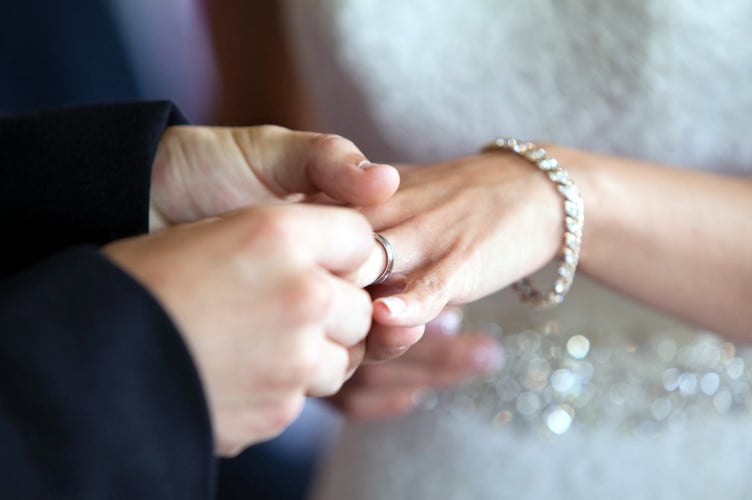 Groom putting the ring on the bride’s finger